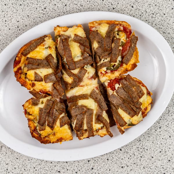 Six rectangular slices of Santorini Pizza & Pasta's gyro pizza, topped with cheese and meat strips.
