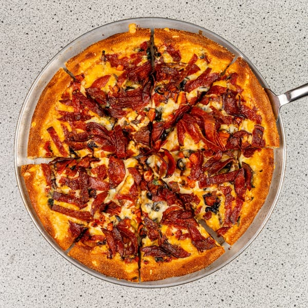 A sliced Santorini Pizza & Pasta pizza with pepperoni, cheese, and olives on a metal pan.