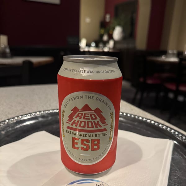 A red and white Red Hook ESB beer can sits on a silver tray in a restaurant.