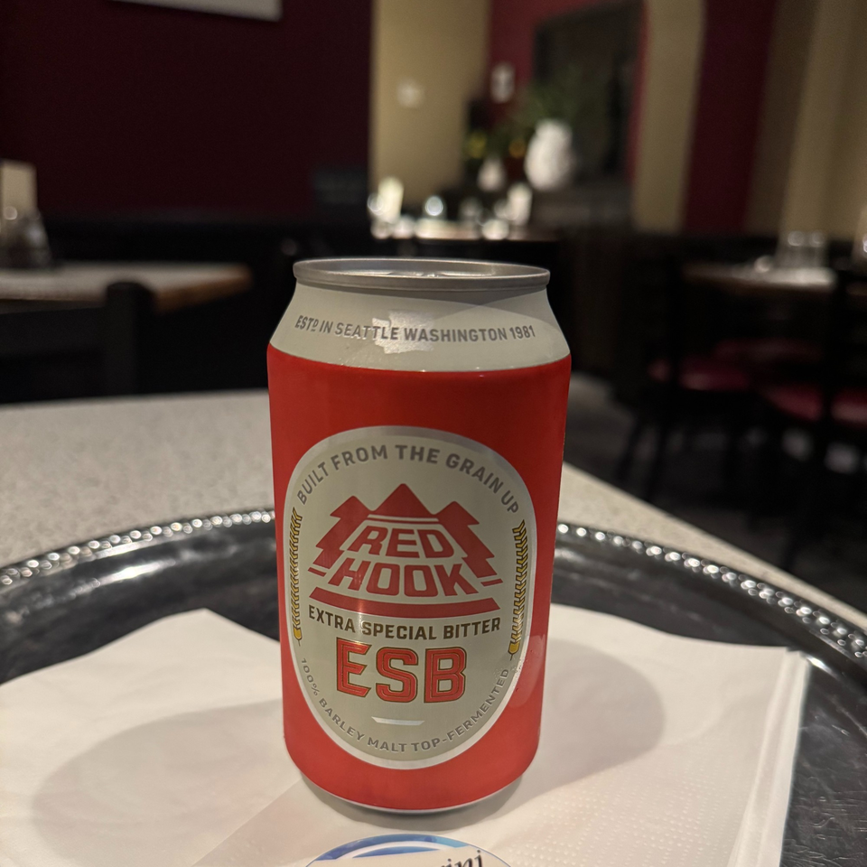 A red and white Red Hook ESB beer can sits on a silver tray in a restaurant.