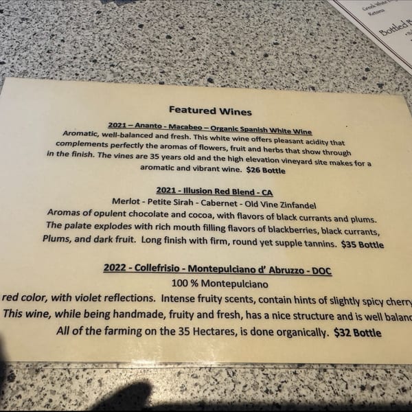 A close-up view of Santorini Pizza & Pasta's featured wines menu on a speckled countertop.