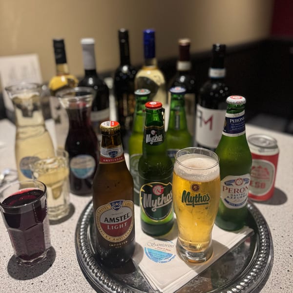 A tray of various beers, wines, and a Santorini Pizza & Pasta napkin on a table.
