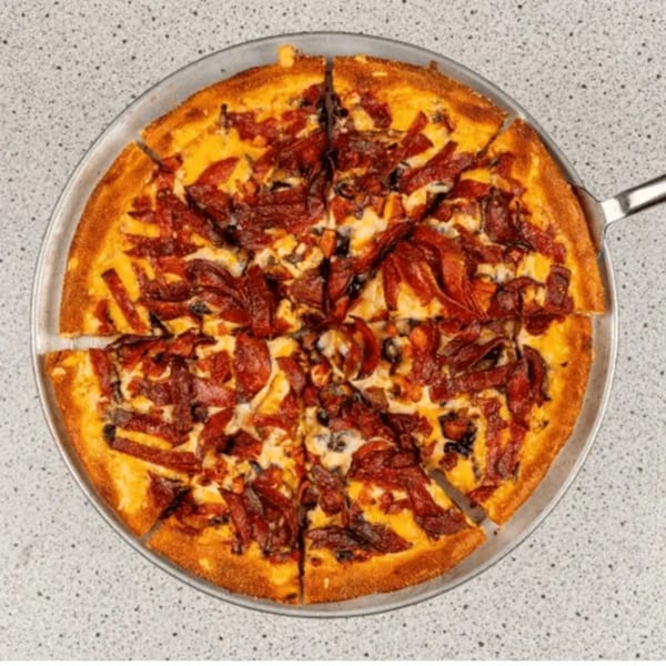 A Santorini Pizza & Pasta pizza with a thick crust, topped with cheese and pepperoni, on a metal pan.