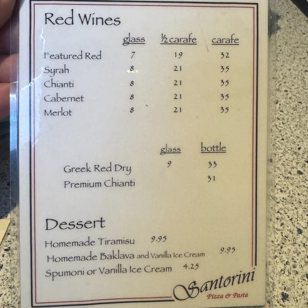 A menu from Santorini Pizza & Pasta showing red wines and desserts with prices.