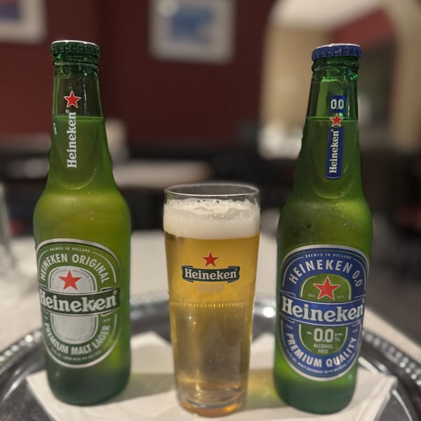 Two Heineken beer bottles and a glass of beer on a silver tray at Santorini Pizza & Pasta.